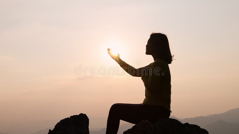 Silhouette van de vrouw die bidt met geloof in religie en geloof in god op de hoge berg waar de zon op het punt staat te dalen