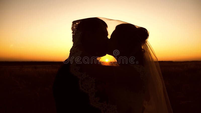 Silhouette van een stel dat verliefd is op het zoenen in het zonsondergang licht Fijne jonge huwelijksreis Gehuwd leven van de me