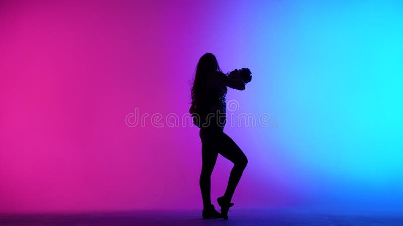 Silhouette von schlanken Cheerleader tanzen energisch mit Pompoms in den Händen vor dem Hintergrund der rosa blauen Lichter in stock video footage