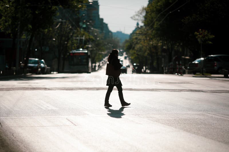 Silhouette of a woman crossing a road in downtown Bucharest during the covid-19 lockdown at dusk
