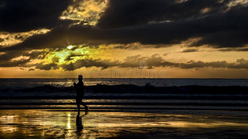 Silhouette of a woman jogging and watching the sunrise on Camboriu beach, Brazil stock photo Silhouette of a woman jogging and watching the sunrise on Camboriu beach, Brazil stock photo