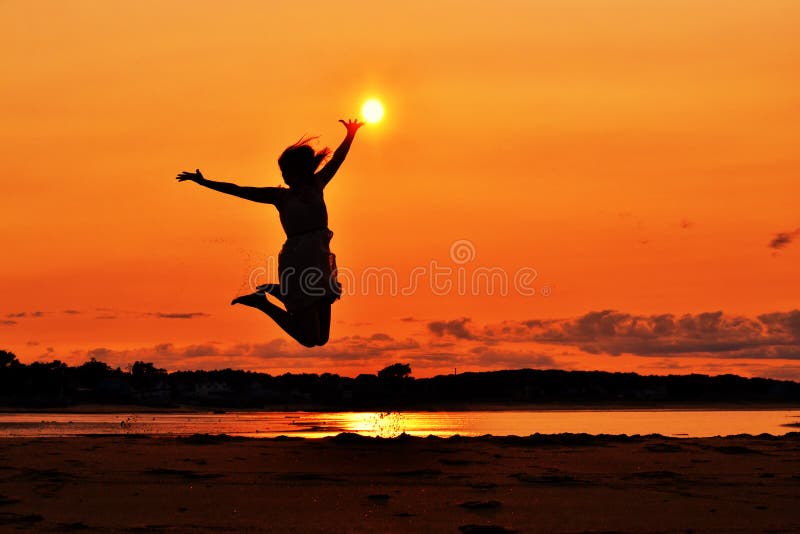 Silhouette of a woman jumping at sunset, touching