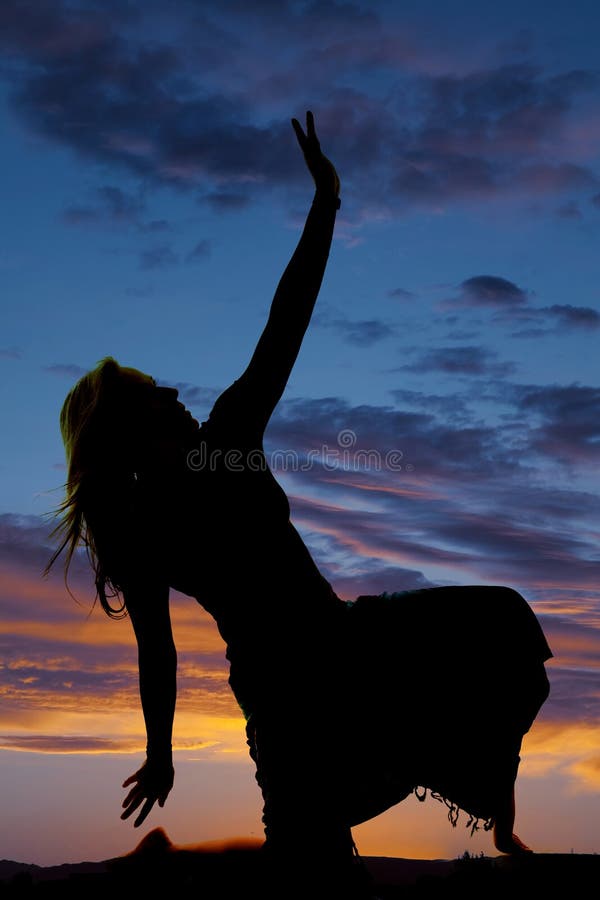 Silhouette of a woman in a skirt kneel hand up