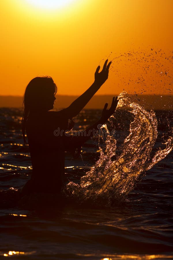 Silhouette of woman at sunset with a splash