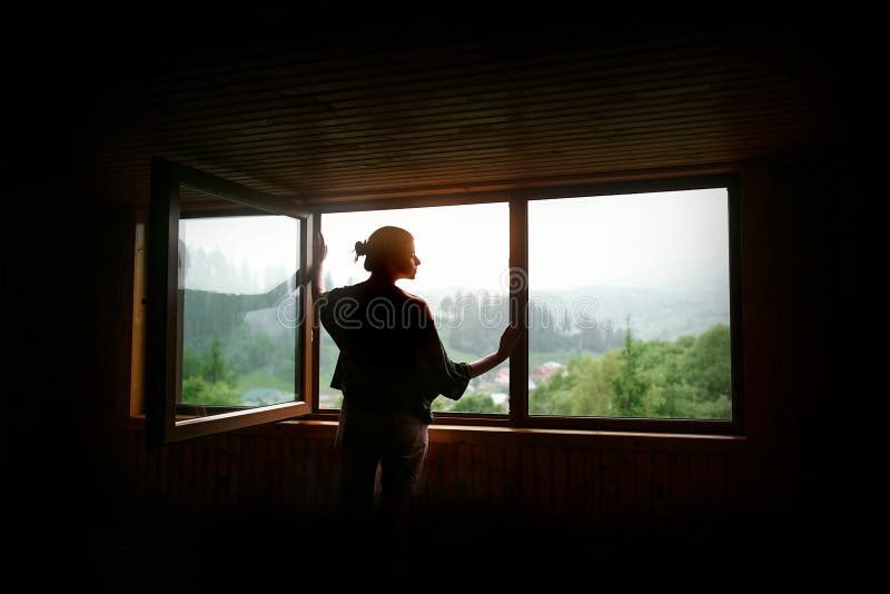 Silhouette of woman in sunshine at big wooden window with view o stock photo Silhouette of woman in sunshine at big wooden window with view o stock photo