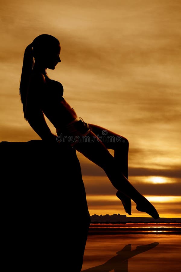 Silhouette woman touch toe in water sunset