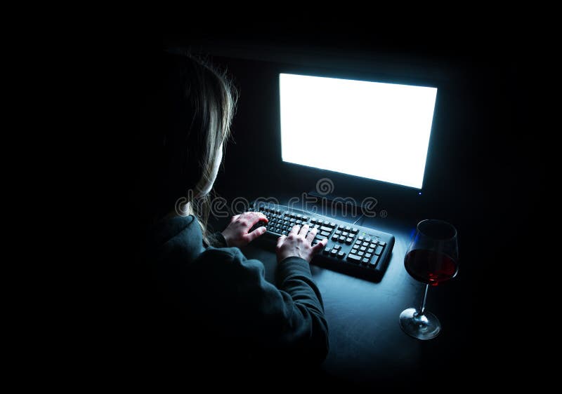 Silhouette of woman typing at computer in dark illuminated by screen royalty free stock photos