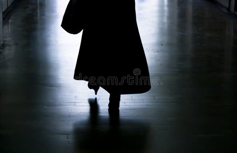 Silhouette of a woman walking away in dark alley