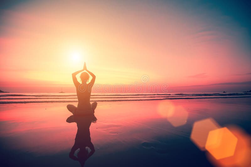 Silhouette of a woman yoga on sea sunset. Relax.