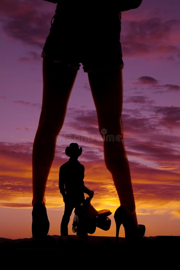 Silhouette womans legs with heels away cowboy saddle