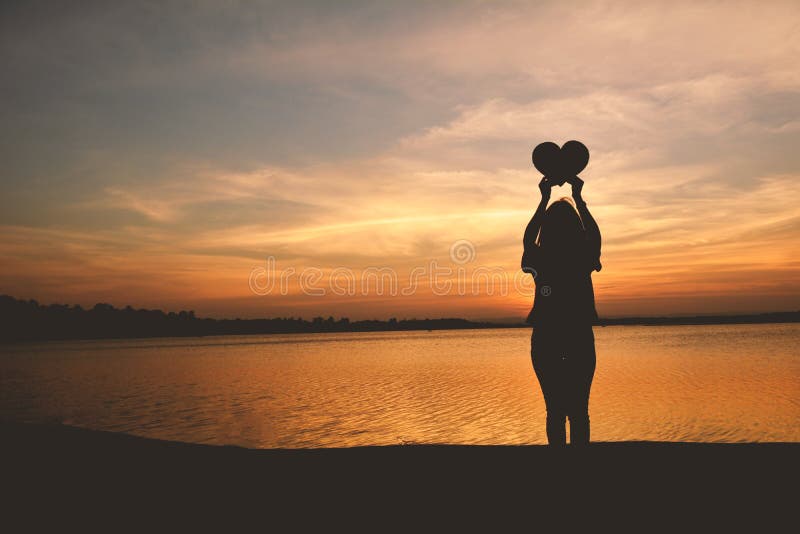 Silhouette of women hands holding heart shape stock photography