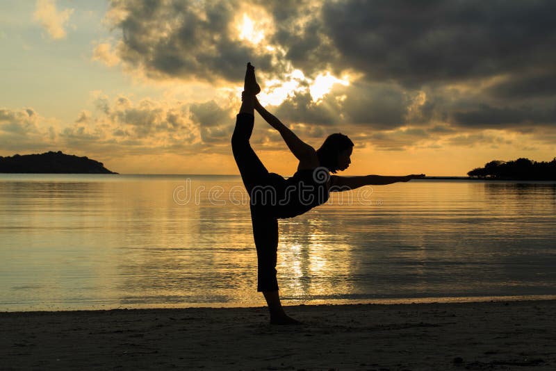 Silhouette yoga girl at sunrise on the beach