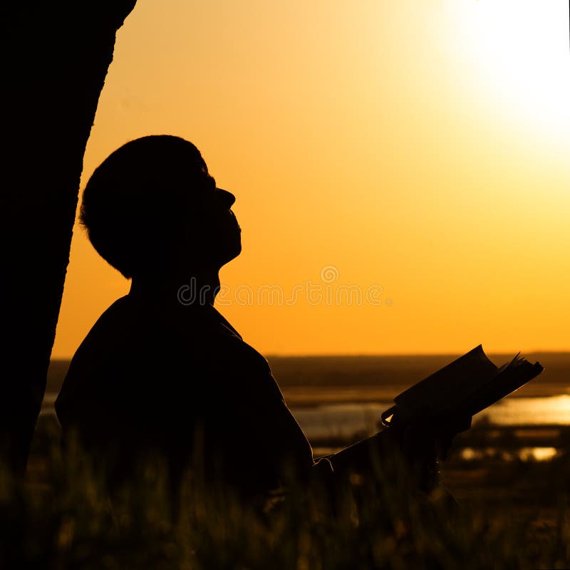 Silhouette of a man reading the Bible in the field, male praying to God in nature, the concept of religion and spirituality stock photos Silhouette of a man reading the Bible in the field, male praying to God in nature, the concept of religion and spirituality stock photos