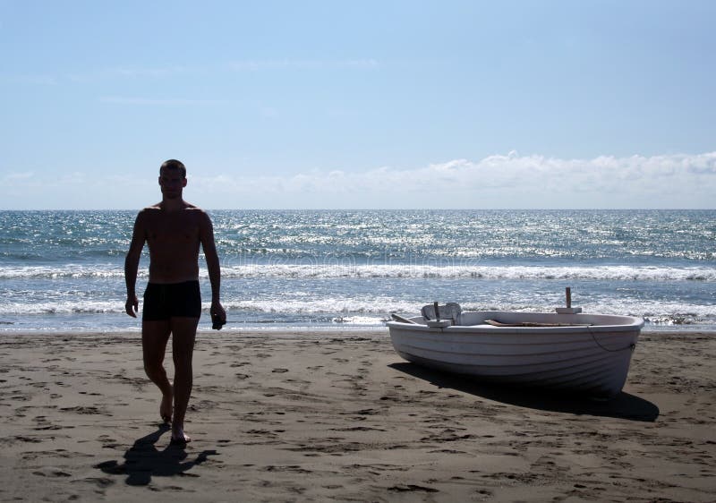 Silhouette of young man walking on a beach stock photos