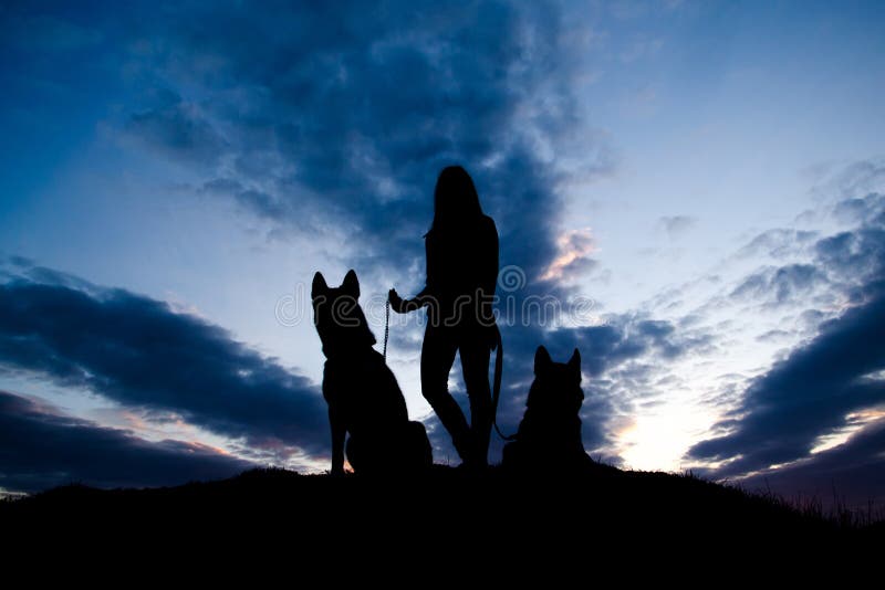 Silhouette of young woman and dog against sky. Summertime. Wild nature. Trendy color.