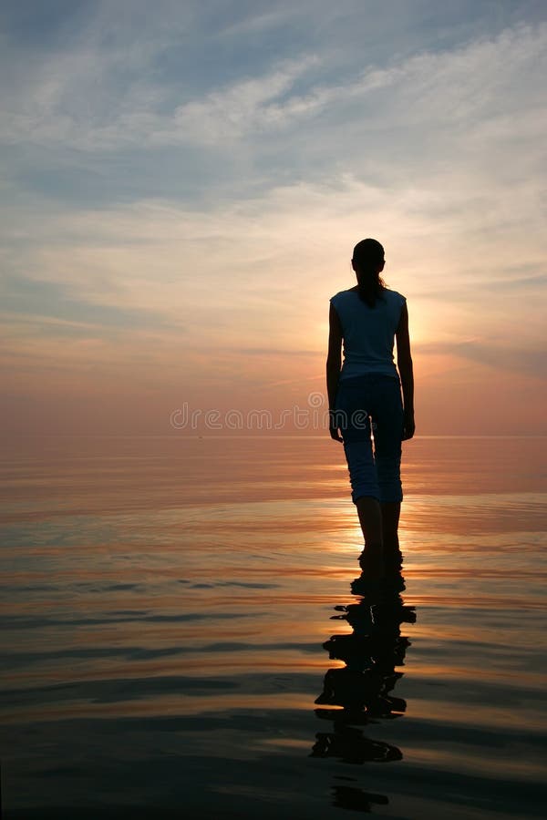 Silhouette of young woman standing in a water