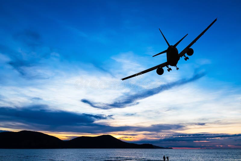 Silhouetted commercial airplane flying at sunset