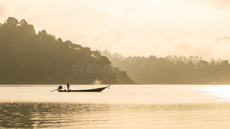 Silhouetted fisherman and boat with mountain background royalty free stock photography Silhouetted fisherman and boat with mountain background royalty free stock photography