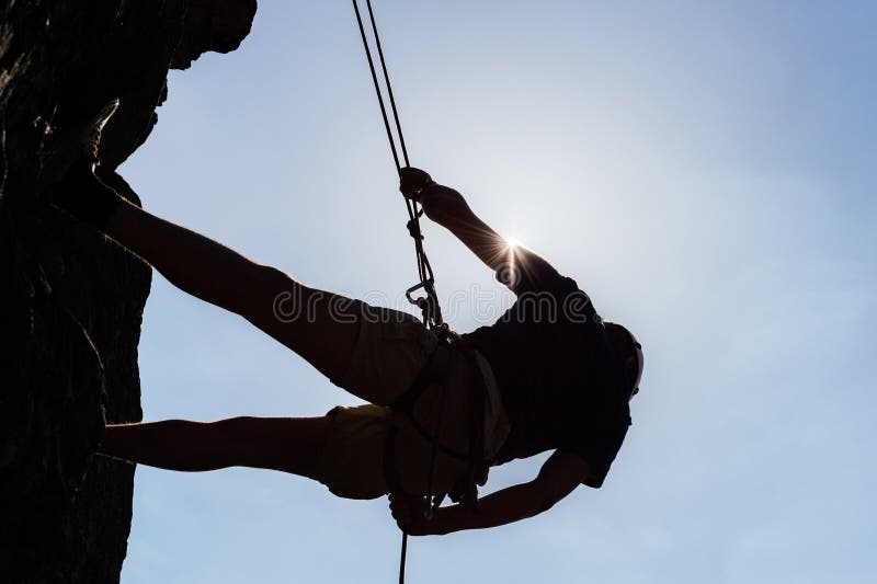 Silhouetted Man Climbing Rock