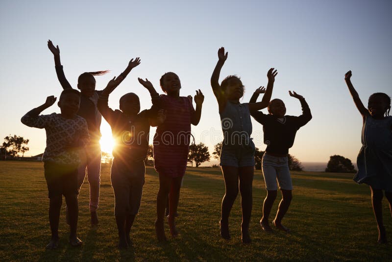 Silhouetted school kids jumping outdoors at sunset stock photo Silhouetted school kids jumping outdoors at sunset stock photo