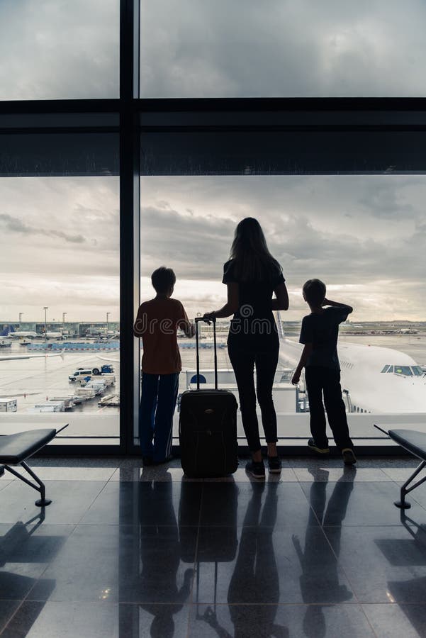 Silhouetten van mamma met jonge geitjes in terminal die op vlucht wachten stock afbeeldingen Silhouetten van mamma met jonge geitjes in terminal die op vlucht wachten stock afbeeldingen