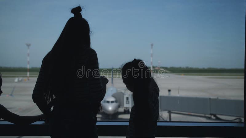 Silhouetten von zwei Schwestern in der Lobby des Flughafens stehen am Fenster und schauen die Flugzeuge auf der Piste an