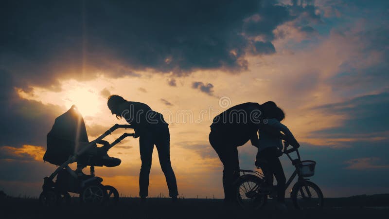 Silhouettes blij familielandjes in de weide bij zonsondergang. begrip ouderschap en mens.