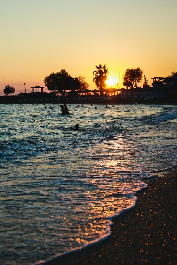 Silhouettes des personnes heureuses nageant et jouant en mer au coucher du soleil, concept au sujet de avoir l'amusement sur la p photos libres de droits Silhouettes des personnes heureuses nageant et jouant en mer au coucher du soleil, concept au sujet de avoir l'amusement sur la p photos libres de droits