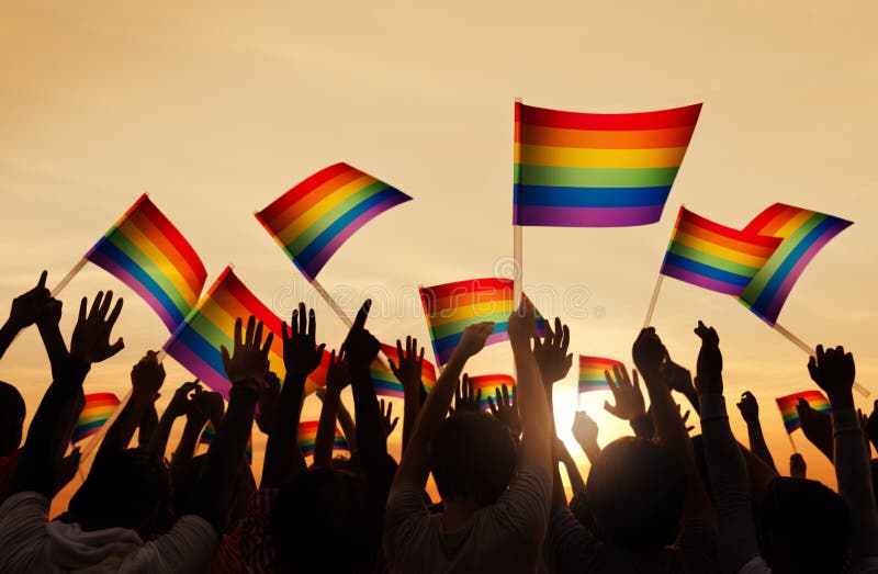 Silhouettes des personnes tenant le drapeau gai de Pride Symbol photographie stock libre de droits Silhouettes des personnes tenant le drapeau gai de Pride Symbol photographie stock libre de droits