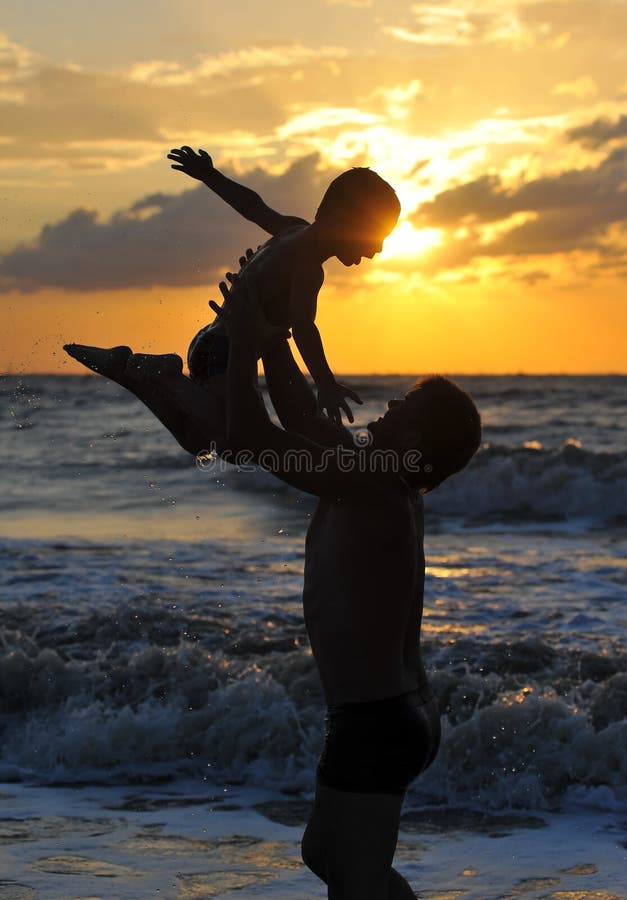 Silhouettes of man and child on the beach