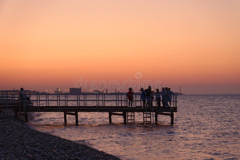 Evening revelers on the beach and in the sea on pane e pomodoro beach at sunset, bari, italy. Evening revelers on the beach and in the sea on pane e pomodoro beach at sunset, bari, italy