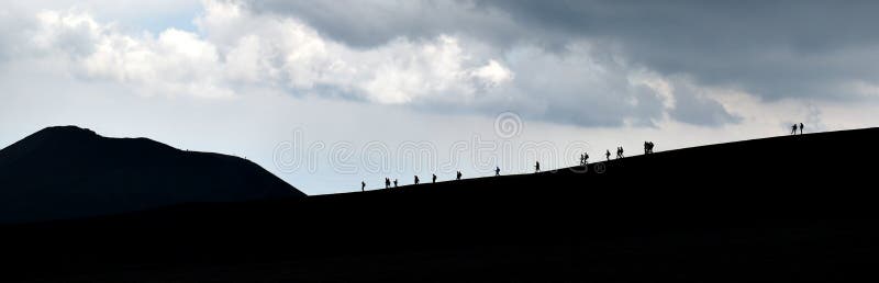 Silhouettes of tourists, walking downhill, on the horizon, dark background
