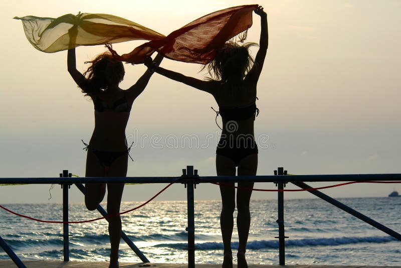 Silhouettes of two girls dancing with scarfs