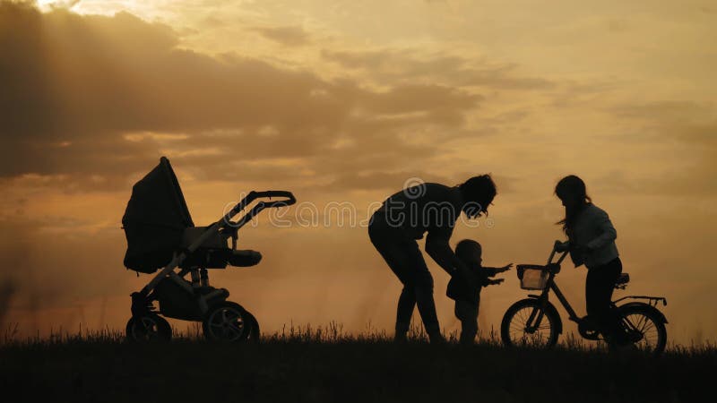 Silhouettes van gelukkige moeder die goed met hun kleine kinderen in het park kunnen omgaan. gelukkig familiesilhouette wandelen i