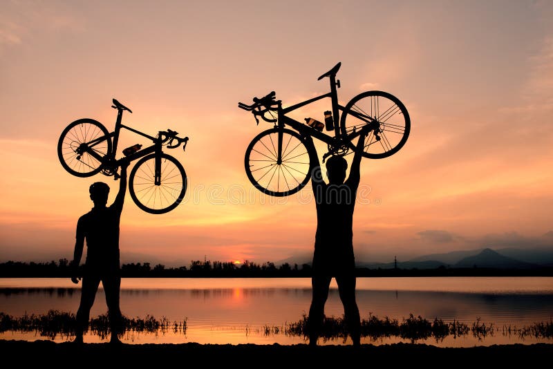 Silhouettez le support pour deux hommes dans la bicyclette de levage d'action au-dessus de sa tête photos libres de droits Silhouettez le support pour deux hommes dans la bicyclette de levage d'action au-dessus de sa tête photos libres de droits