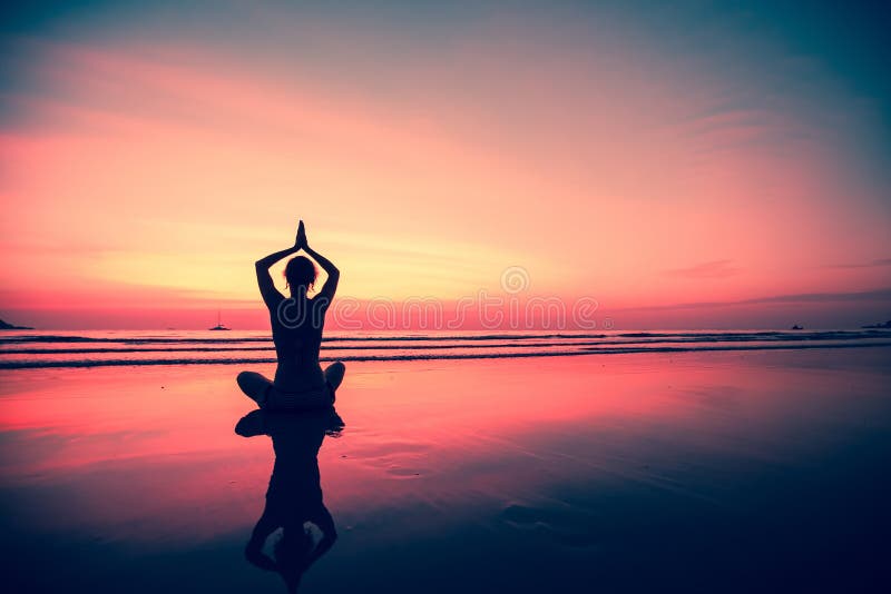 Silhouettez le yoga de pratique de jeune femme sur la plage au coucher du soleil nature image stock Silhouettez le yoga de pratique de jeune femme sur la plage au coucher du soleil nature image stock