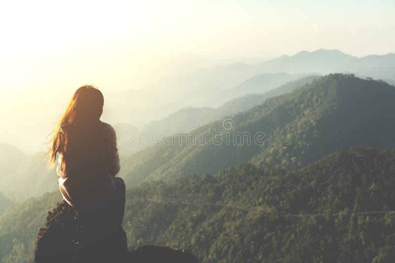 Silhouettieren Sie die Frau, die auf Berg am Morgen und an Weinlese filt sitzt lizenzfreies stockbild
