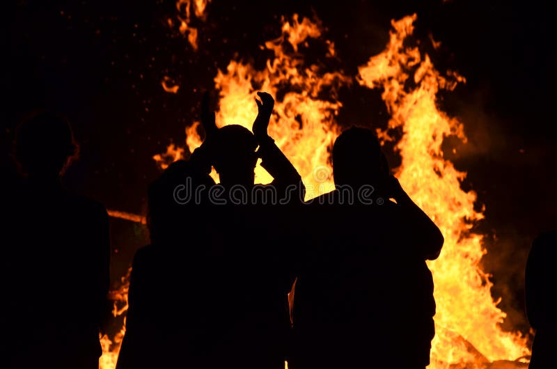 Silhouettiert junge Leute um Brüllenflammen-Feuerfeuer