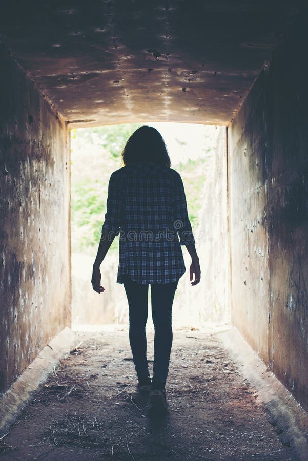 Silhueta da caminhada da mulher do moderno no túnel Luz na extremidade do Tun imagem de stock Silhueta da caminhada da mulher do moderno no túnel Luz na extremidade do Tun imagem de stock