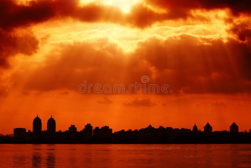 A silhueta da cidade e o céu vermelho com sol irradiam