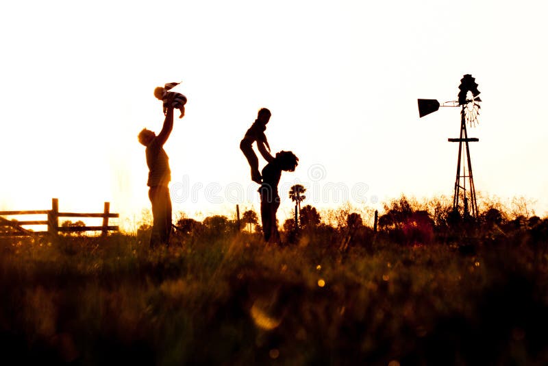Silhueta da família no campo com moinho de vento imagem de stock Silhueta da família no campo com moinho de vento imagem de stock