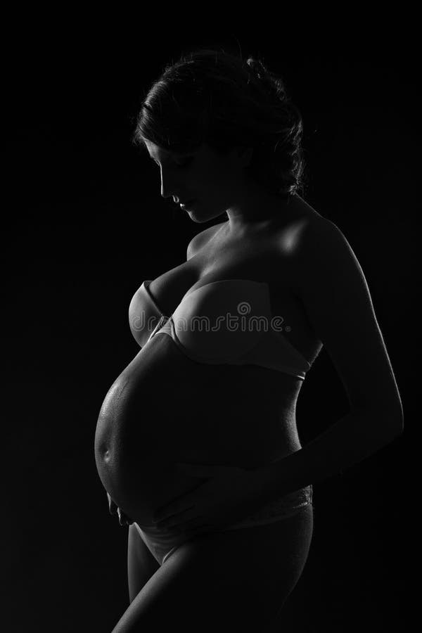 Silhueta da mulher gravida sobre o fundo preto. Vista lateral. imagem de stock Silhueta da mulher gravida sobre o fundo preto. Vista lateral. imagem de stock