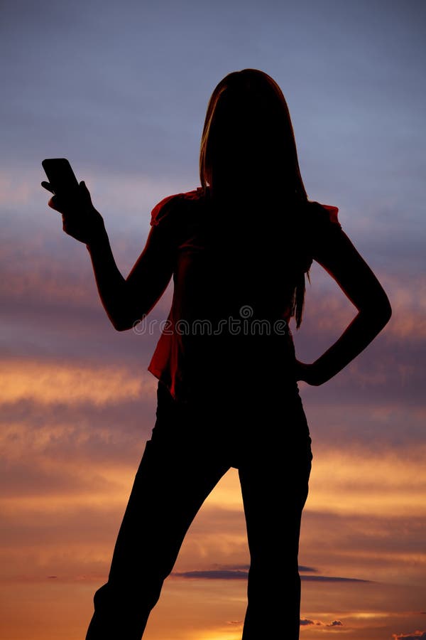Silhueta da mulher que guardara para fora o por do sol do telemóvel. fotos de stock royalty free Silhueta da mulher que guardara para fora o por do sol do telemóvel. fotos de stock royalty free