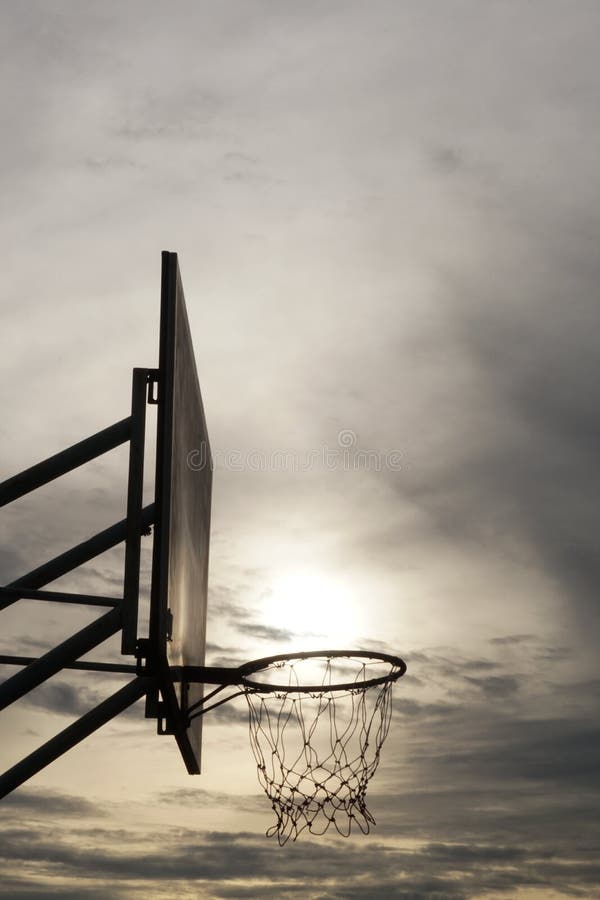 Silhueta de aro de basquete com pôr do sol e nuvens foto de stock royalty free