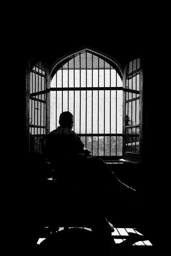 Silhueta de um homem sentado no escuro contra a janela