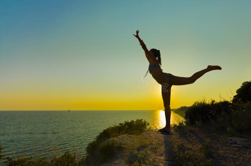 Silhueta de uma menina que faz exercícios no por do sol imagens de stock royalty free Silhueta de uma menina que faz exercícios no por do sol imagens de stock royalty free