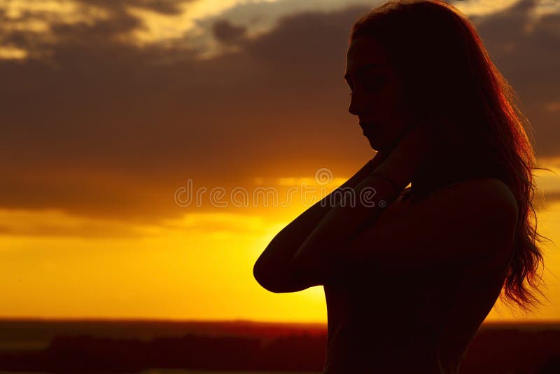 Silhouette of a beautiful romantic girl at sunset , face profile of young woman with long hair in contarst sunlight in hot weather and desert wind. Silhouette of a beautiful romantic girl at sunset , face profile of young woman with long hair in contarst sunlight in hot weather and desert wind