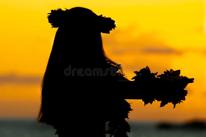 Silhueta de uma mulher havaiana dançando no pôr do sol perto do mar.