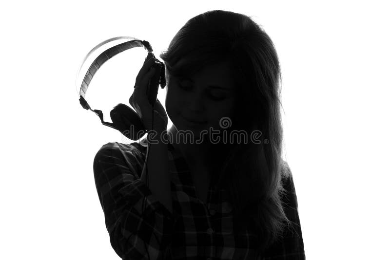 Silhueta de uma mulher posta a seus fones de ouvido da orelha que escutam a música imagens de stock royalty free Silhueta de uma mulher posta a seus fones de ouvido da orelha que escutam a música imagens de stock royalty free