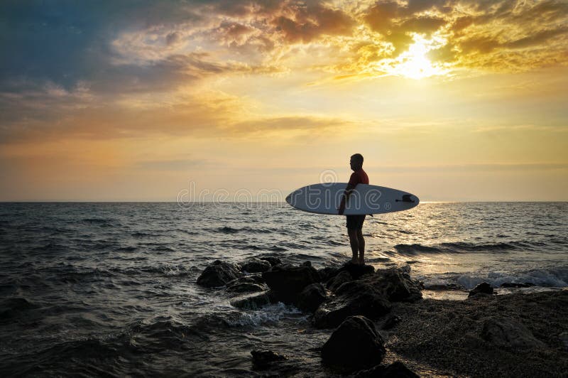 Surfer on a rock at sunset. Surfer on a rock at sunset